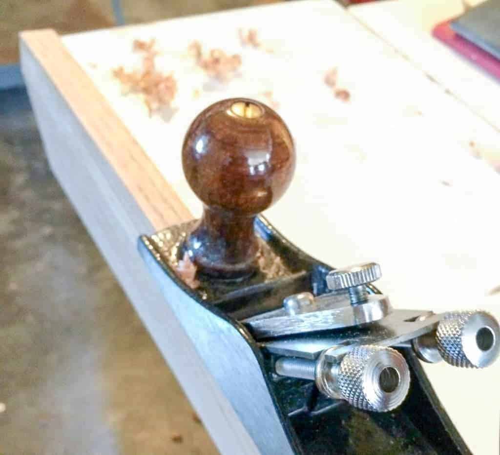 shaving the edge of the door threshold with a block plane