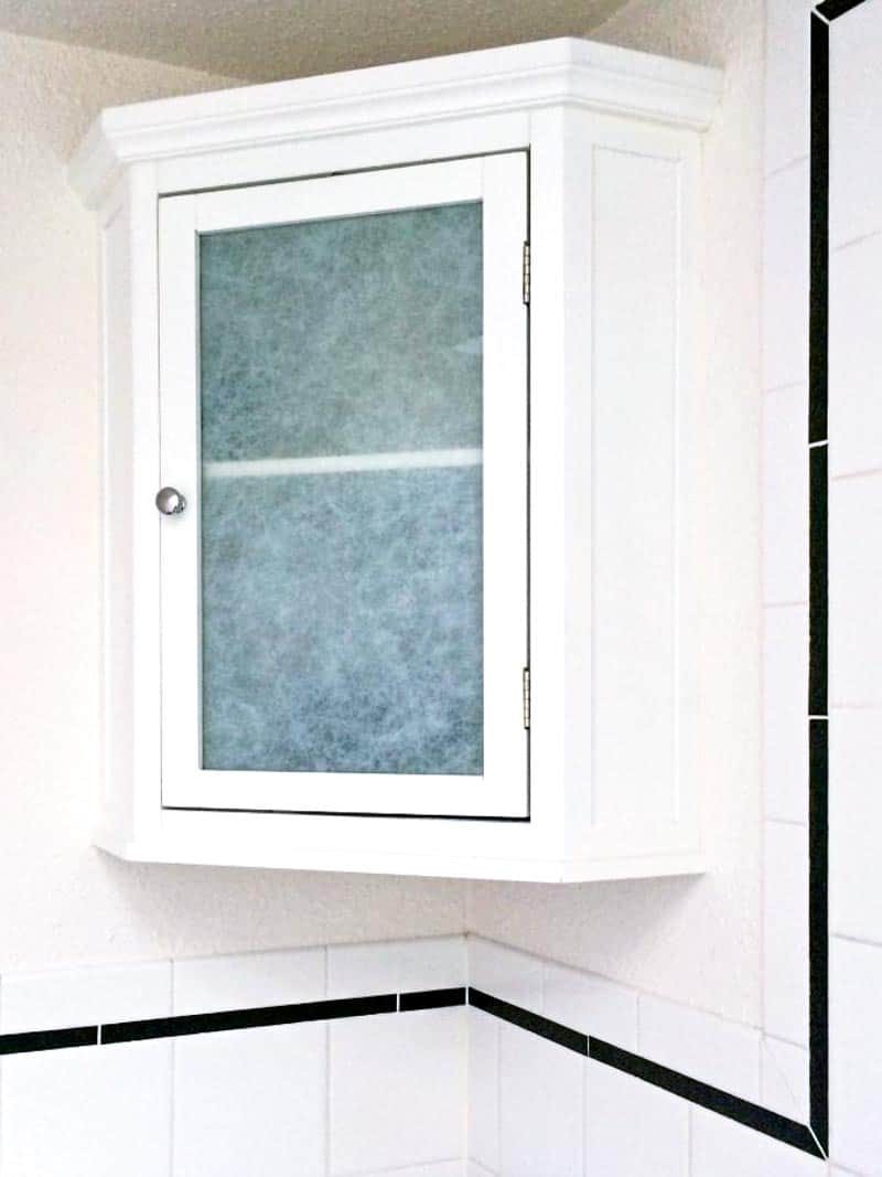 small bathroom corner cabinet with contact paper on glass door