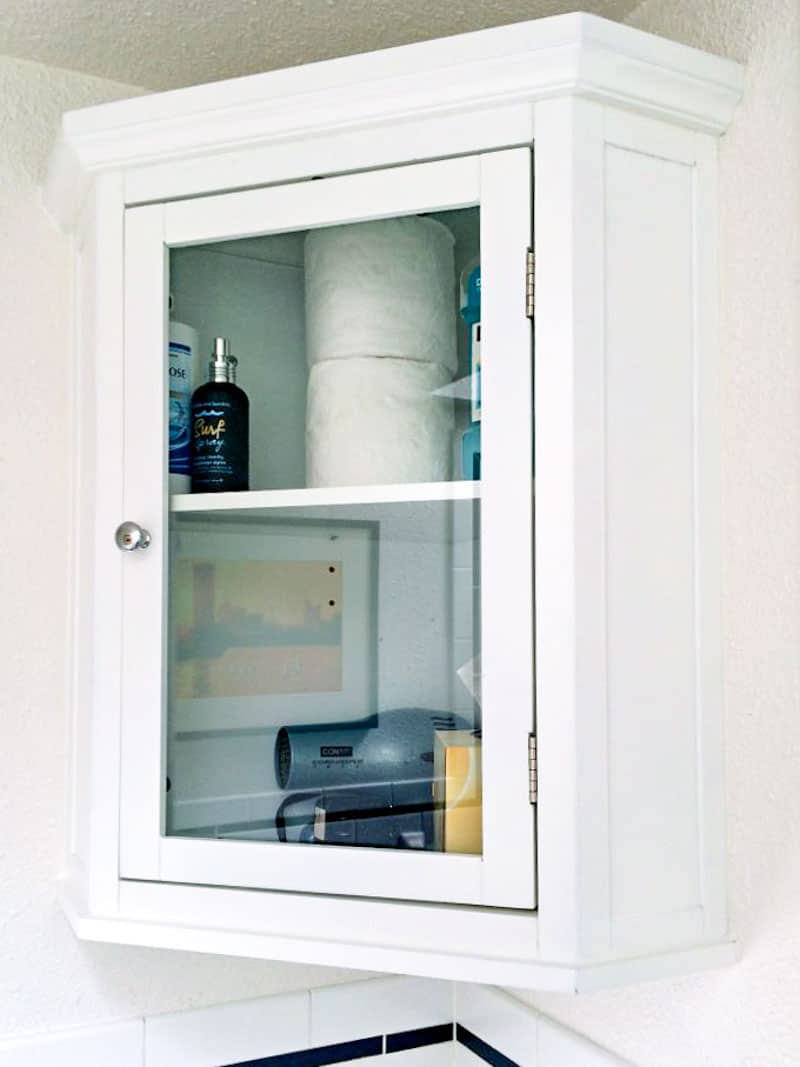 small bathroom corner cabinet with glass door installed on the wall