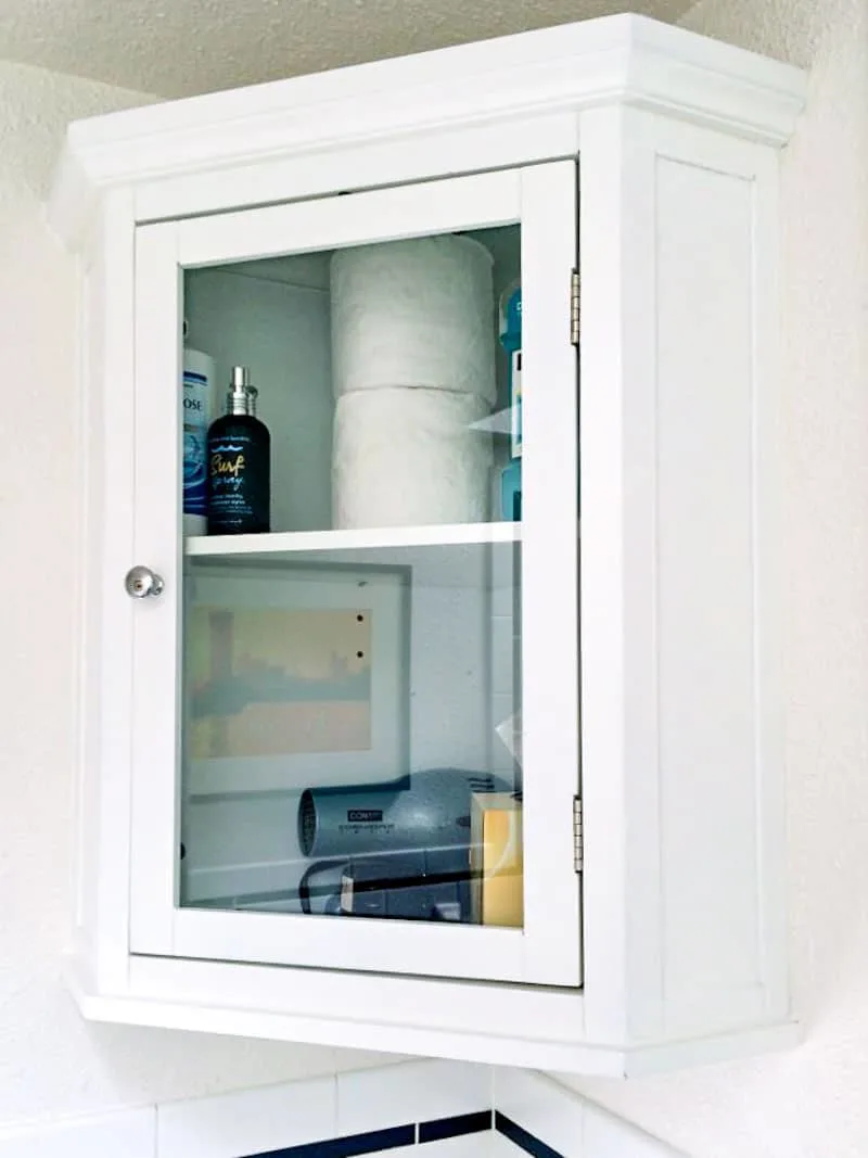 small bathroom corner cabinet with glass door installed on the wall