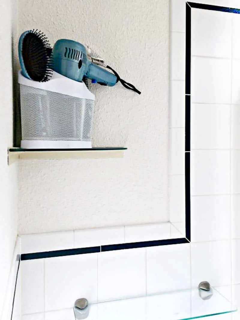 small bathroom corner shelf with hair dryer and brushes