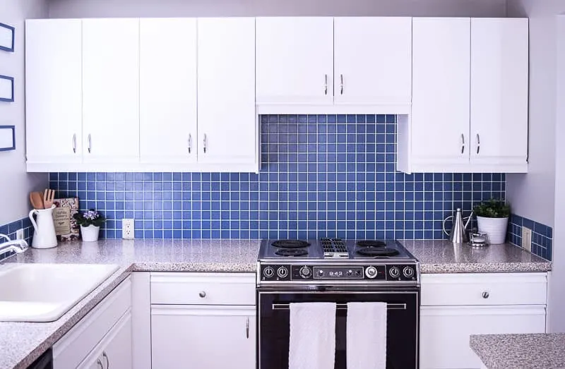 full view of painted kitchen cabinets with blue backsplash