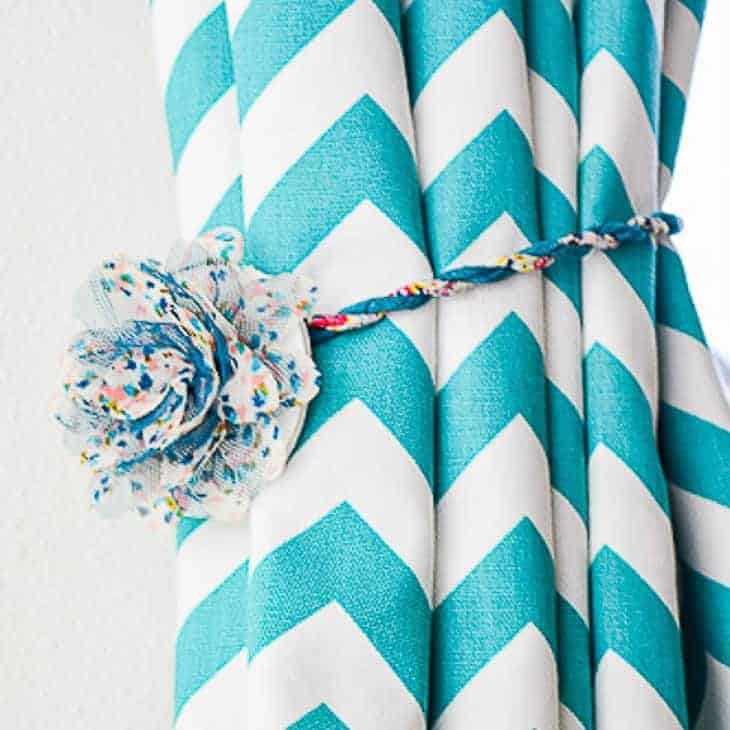 magnetic curtain tie back with flower center around blue and white chevron patterned curtain