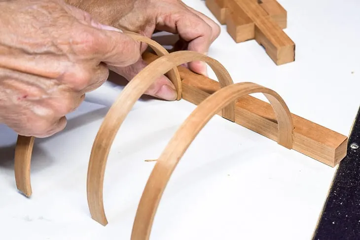 curved wood pieces being fitted into notches for a DIY wall sconce