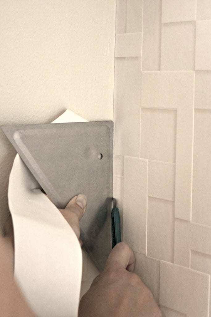 Use a straight edge to trim excess textured wallpaper at the corners for a perfect fit! - The Handyman's Daughter