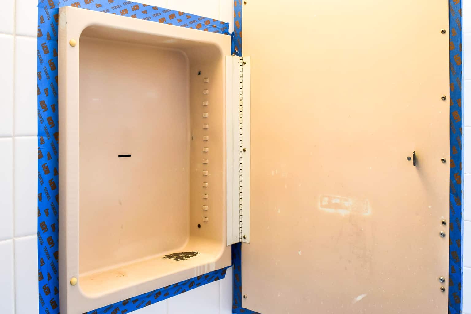 old metal medicine cabinet with painters tape around outside