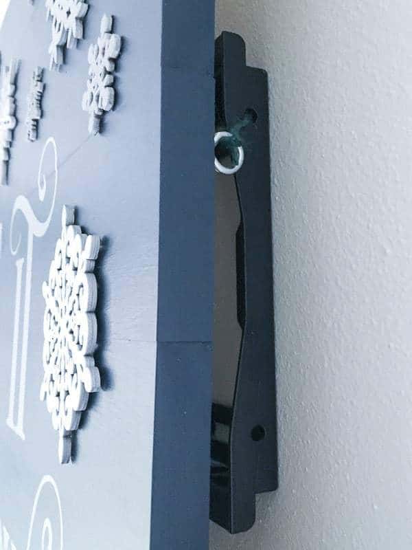 To secure the Let it Snow sign to the wall, I attached screw hooks to the back and tied it to the TV mount bracket behind it.