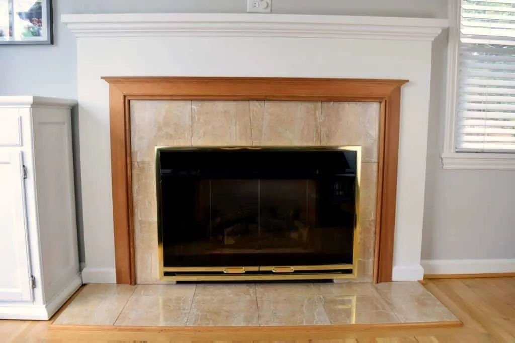 dated fireplace with peach marble tile surround and orange oak trim