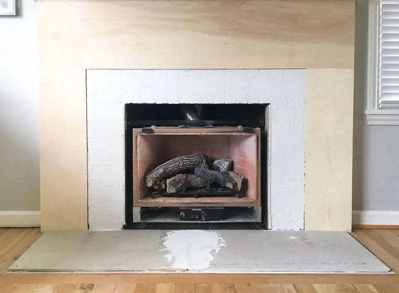 brick fireplace smoothed out with thin set and drywall surround covered with plywood