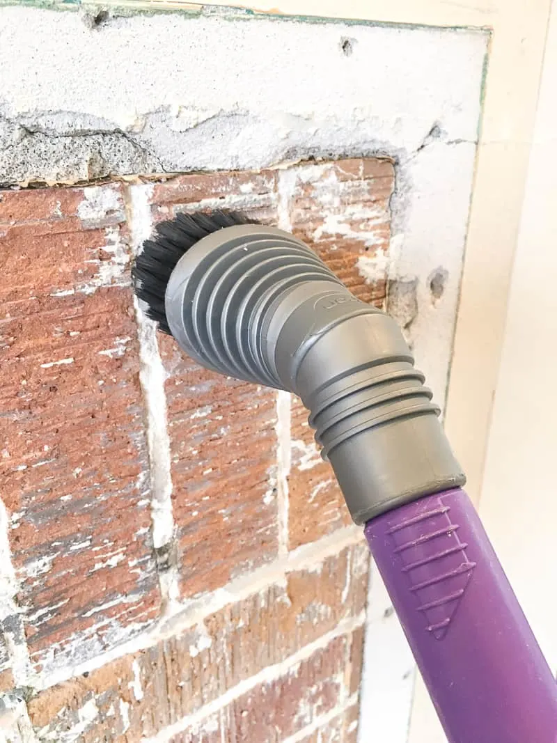 cleaning the brick fireplace with a vacuum before tiling