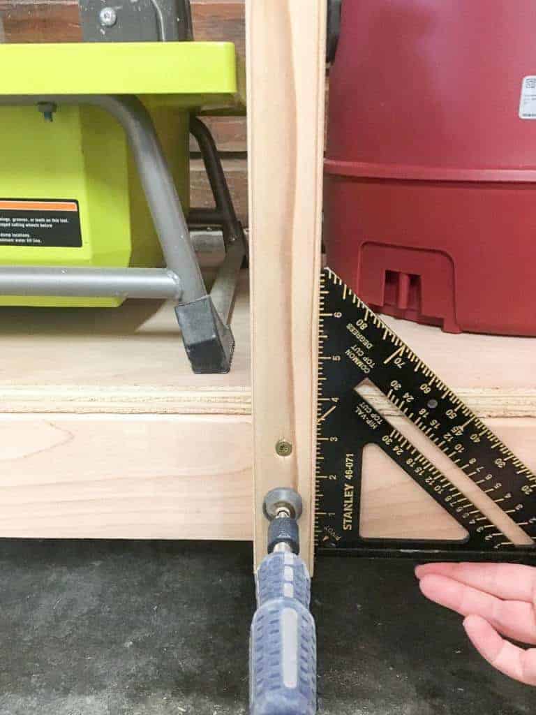 attaching vertical supports for DIY workbench shelves and checking for square