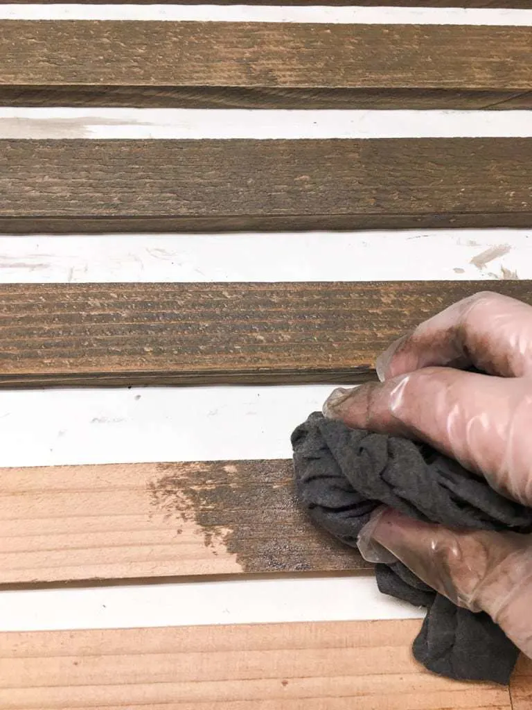 hand applying stain to boards for clematis trellis 