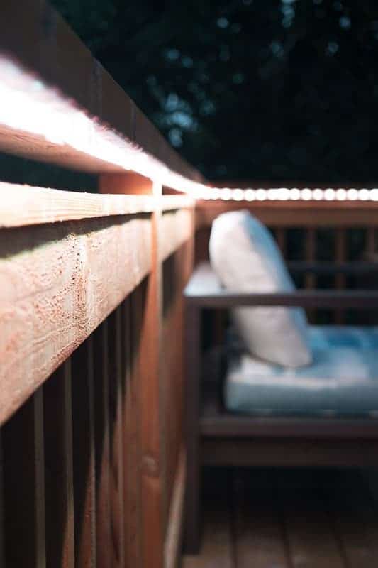 white outdoor rope lights attached to underside of deck railing