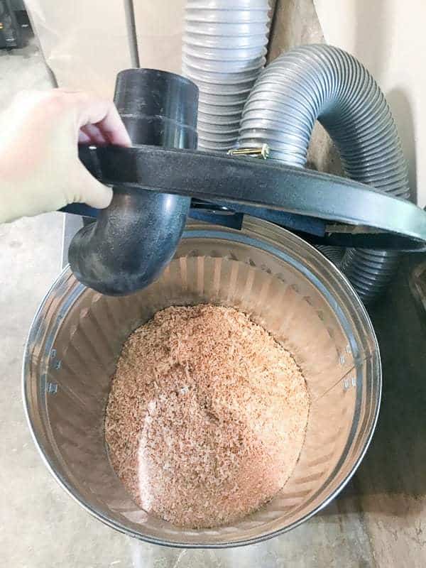 trash can sawdust separator with hand lifting lid to reveal sawdust inside