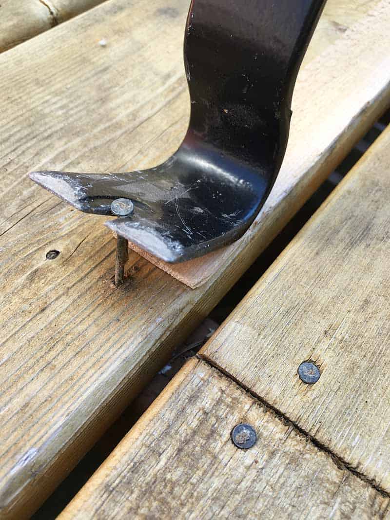 pry bar end of nail puller used to pull out raised nail from deck