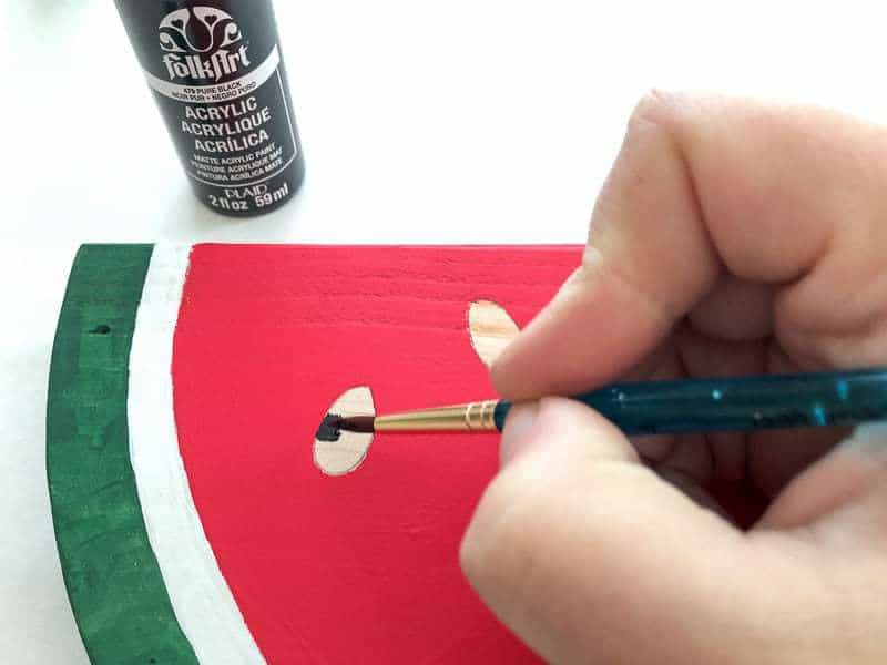 painting the seeds on the wooden watermelon slice