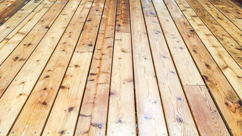 spraying wood brightener on wooden deck