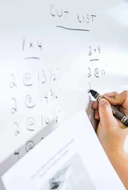 writing cut list on whiteboard wall in workshop