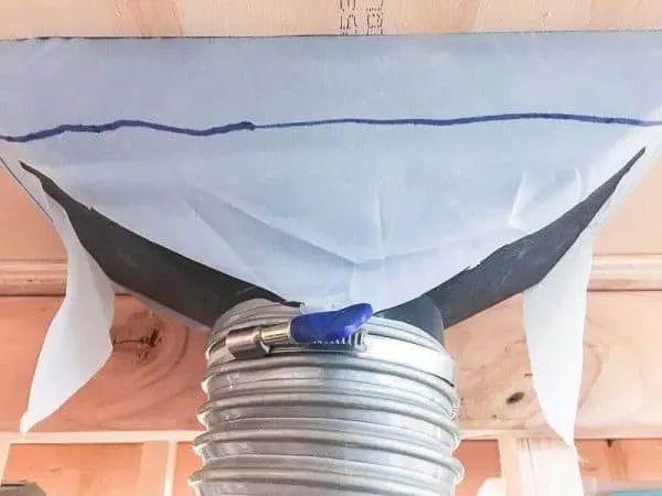 underside of miter saw dust hood with dust collection hose attached to funnel