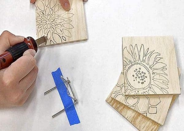 using a wood burning tool to create a design on wooden coasters