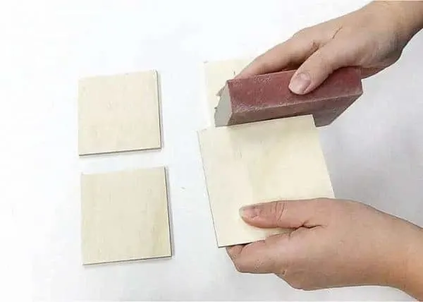 sanding the edges of the plywood coasters with a sanding sponge