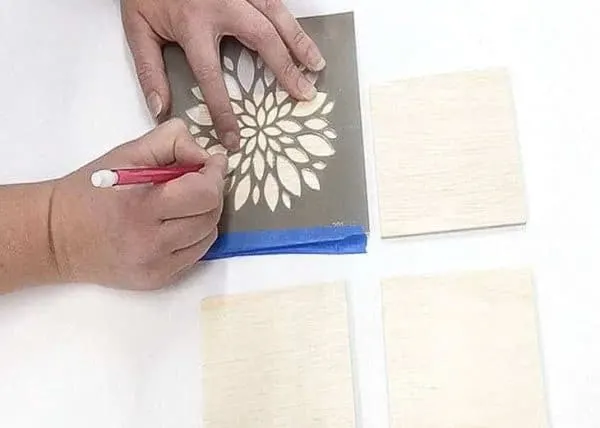 tracing a floral design onto plywood with a stencil