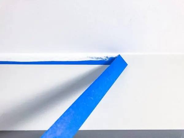 pulling blue painters tape off wall after painting ceiling