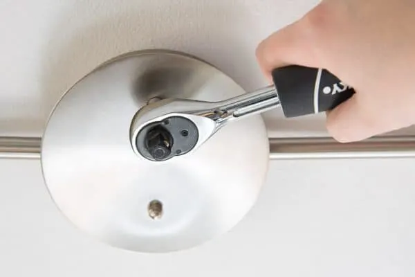socket wrench tightening nuts on track lighting fixture