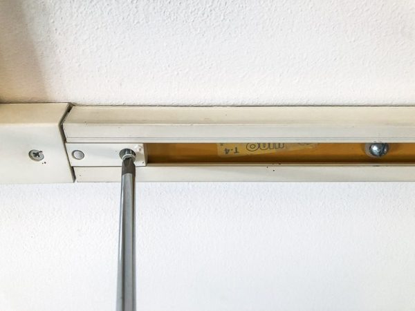 unscrewing track lighting from ceiling with screwdriver