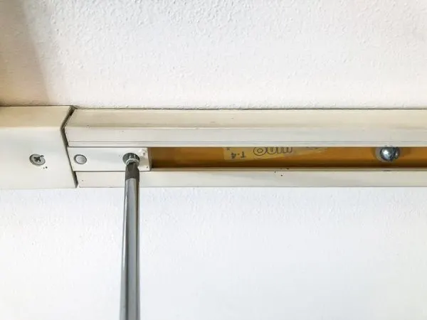 unscrewing track lighting from ceiling with screwdriver