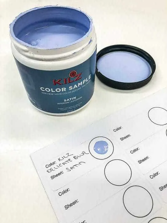 open jar of blue paint with sheet of labels indicating color and sheen