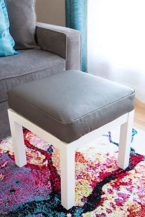 gray leather ottoman with white base next to gray couch
