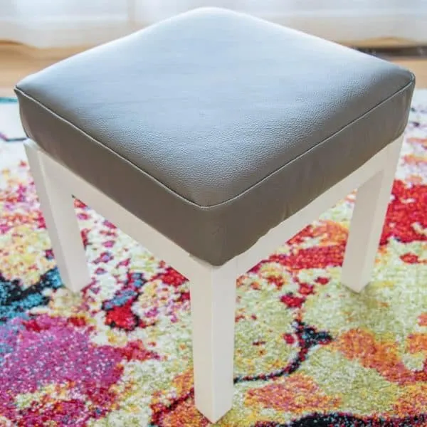 gray leather DIY ottoman cover with white base on colorful area rug