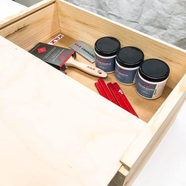 wooden box with paint samples, paint brushes and pencils inside