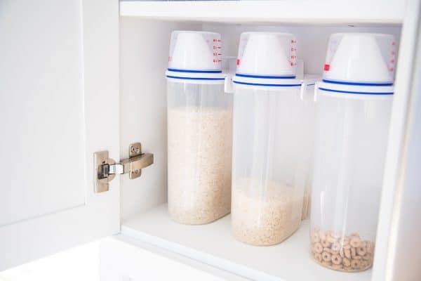 rice containers with measuring cups on pantry shelf