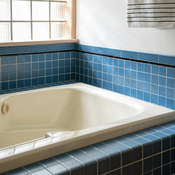 almond bathtub with glass block window and blue tile