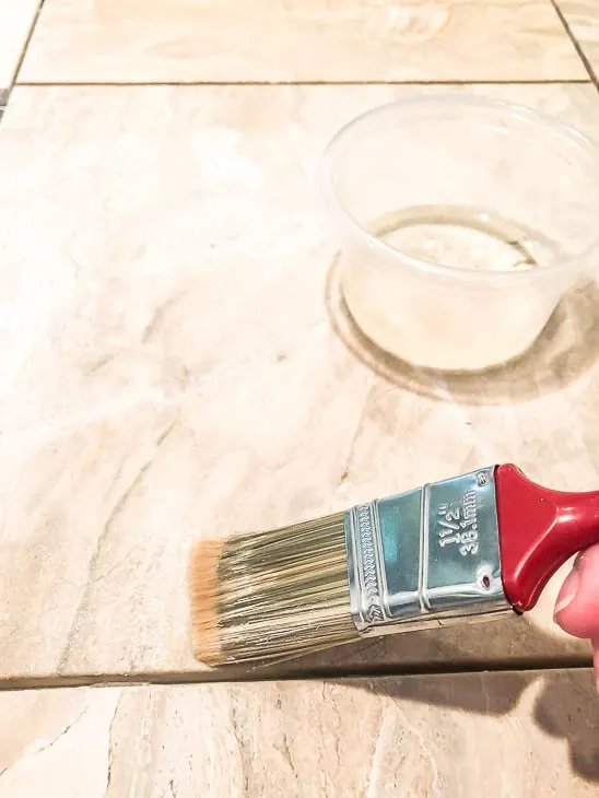 Applying grout release on limestone tile with a paint brush