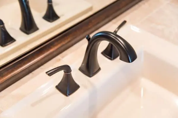 bathroom vanity with limestone tile, almond sink, oil rubbed bronze faucet and mirror frame