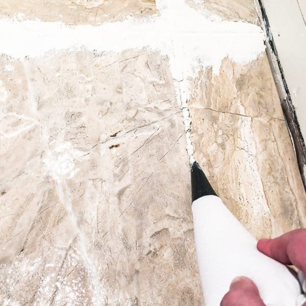grout bag applying grout to limestone tile
