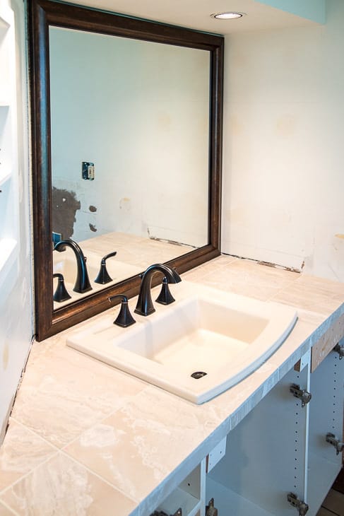 bathroom remodel in progress with limestone tile vanity, almond sink, and mirror frame installed