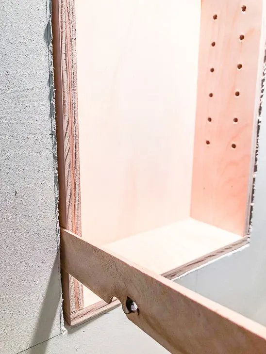 Installing recessed bathroom shelves with shim on one side