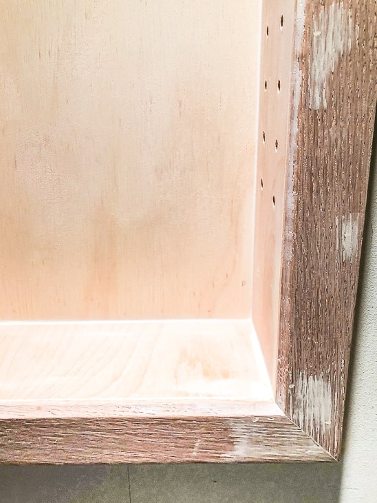 Filling gaps and holes in the recessed bathroom shelves with wood filler and caulk