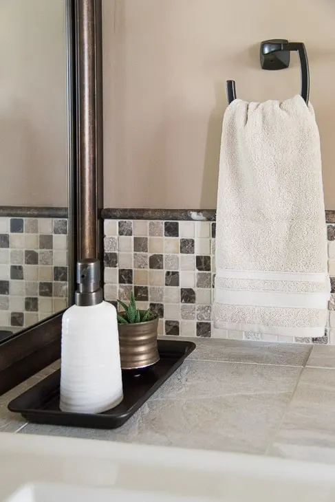 tiled vanity countertop with hand towel ring and framed mirror