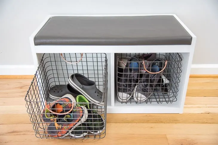 DIY entryway bench with wire bins filled with shoes and one bin pulled out