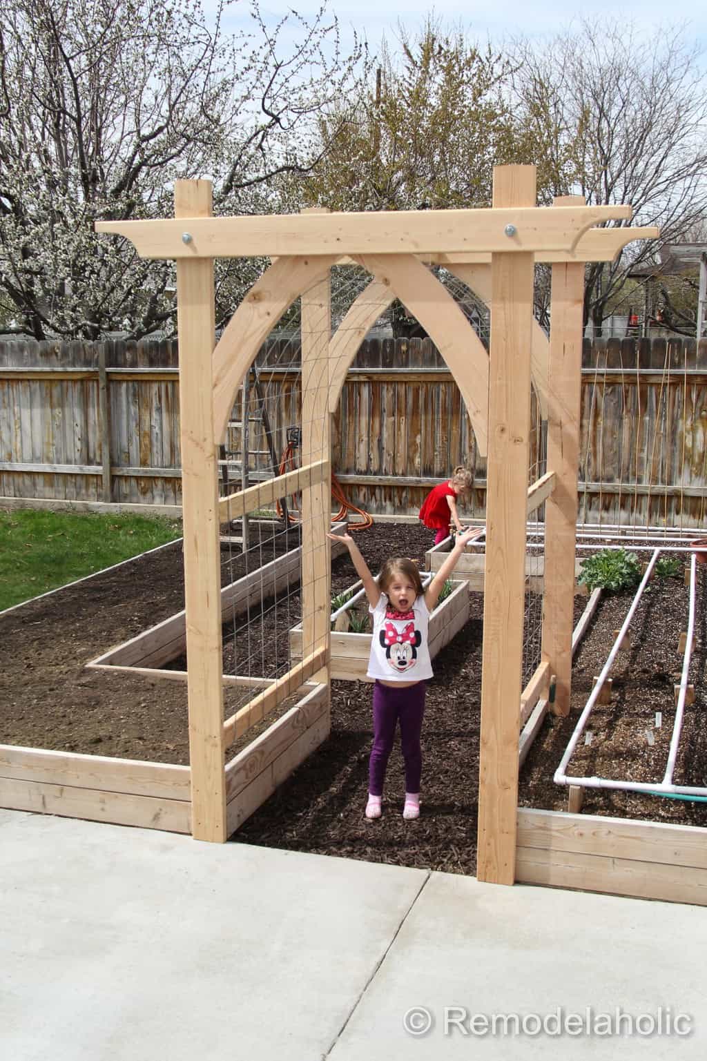 gothic arch arbor at entrance to raised planter bed garden