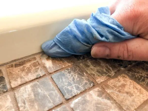applying grout caulk to outside edge of bathtub surround