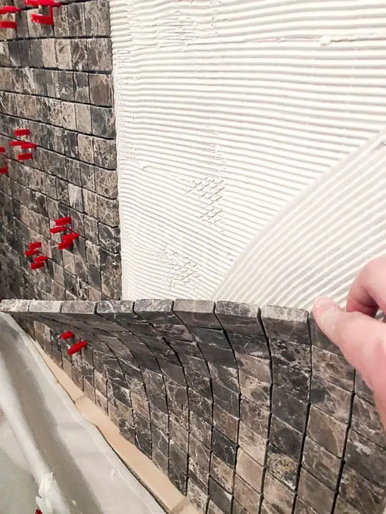 Applying mosaic tile to front of bathtub surround
