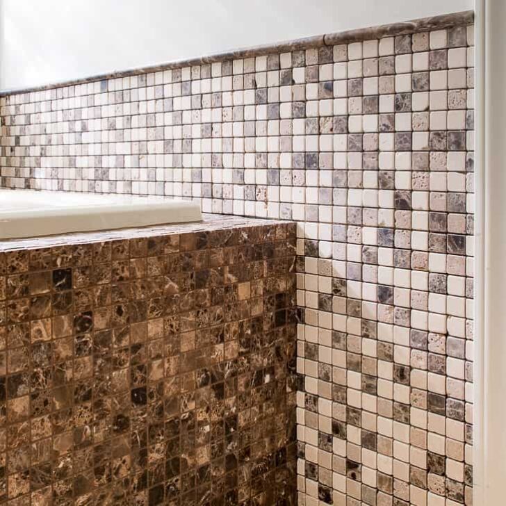 bathtub surround tiled in dark brown mosaic tiles with coordinating wall tile