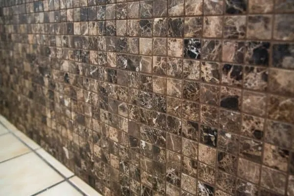 bathtub surround with dark brown tiles and grout