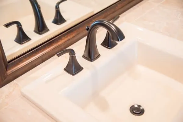 almond sink with oil rubbed bronze faucet and limestone tile countertop